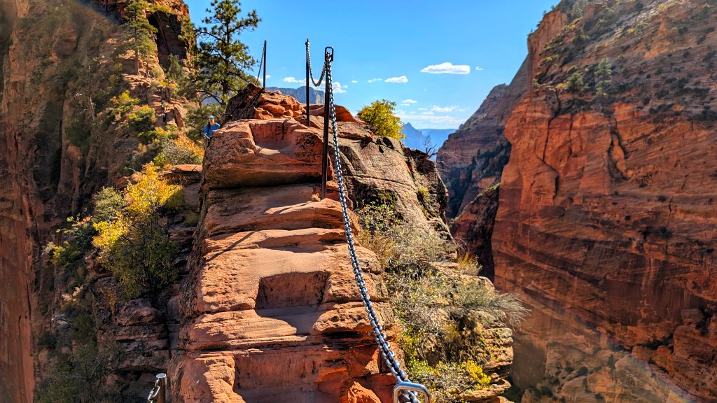 Narrow rocky ridge with chain handrail and steep canyon sides