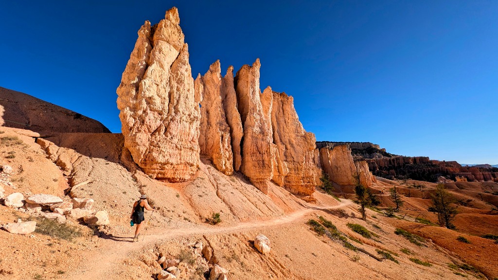 Hiker on the Fairyland Loop trail among towering orange hoodoos at Bryce Canyon National Park