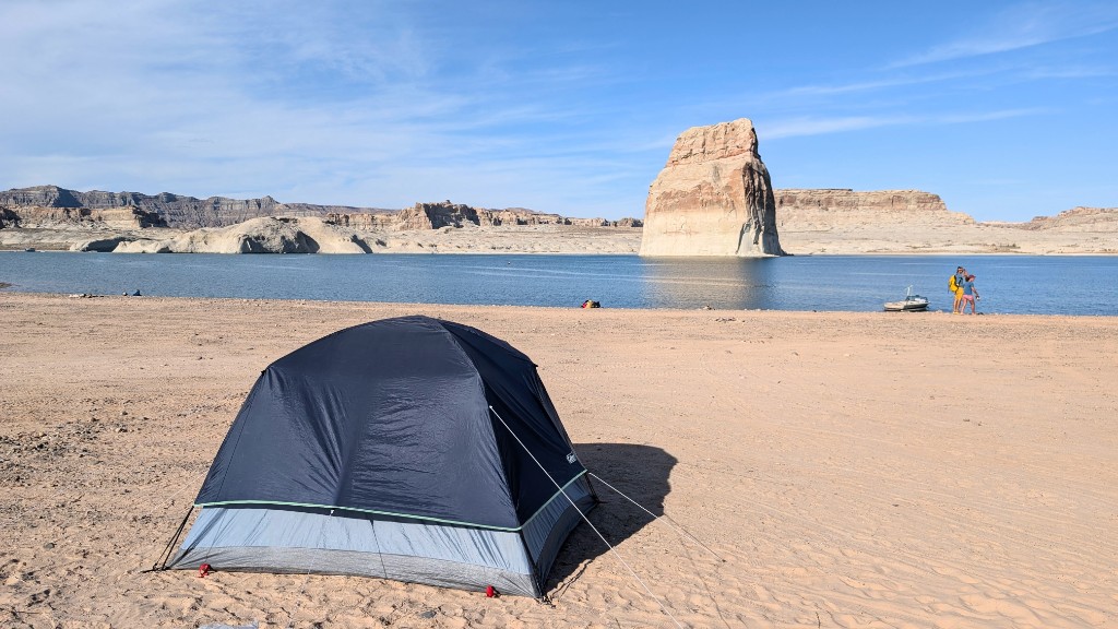 Tent pitched on the sand at Lone Rock Beach Campground with Lake Powell and sandstone formations in the background