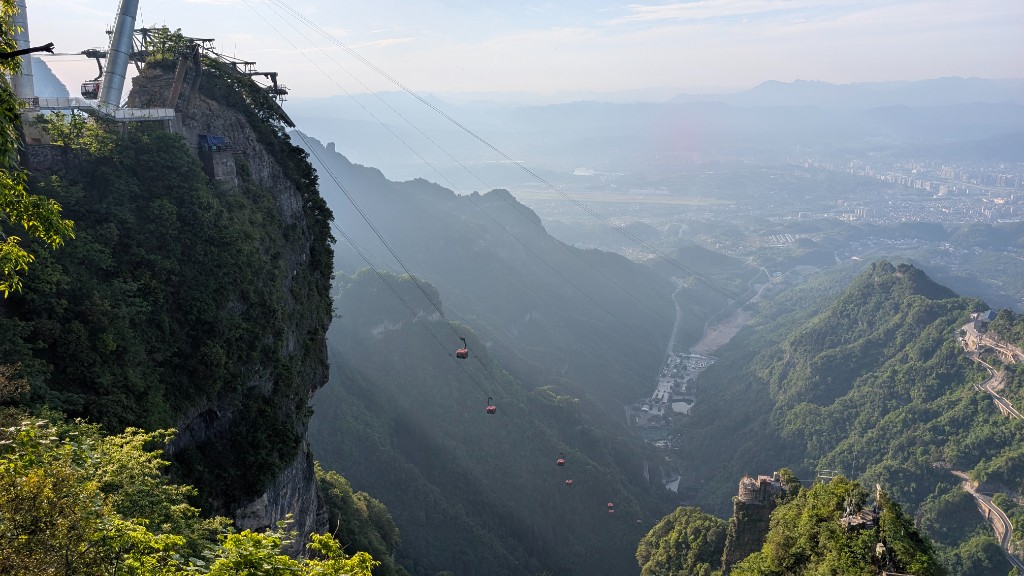 Red cable cars descending from Tianmen Mountain station above a forested valley near Zhangjiajie